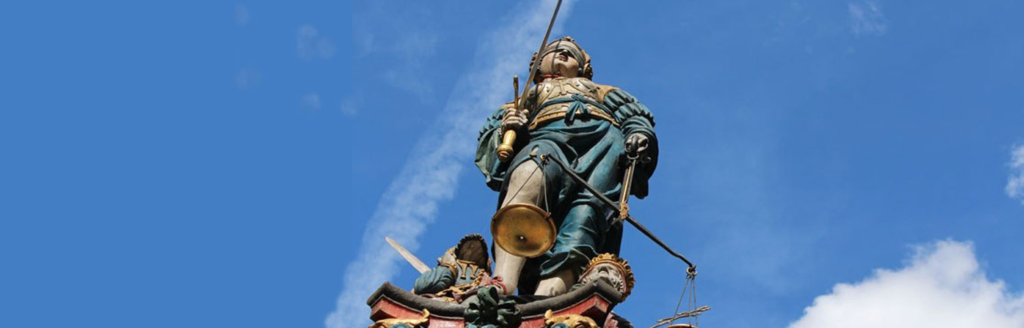 Der Gerechtigkeitsbrunnen, eine Statue, die ein Schwert und eine Wage in der Hand hält.