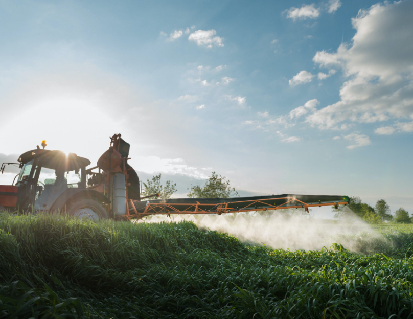 Un tracteur pulvérise des pesticides dans un champ.