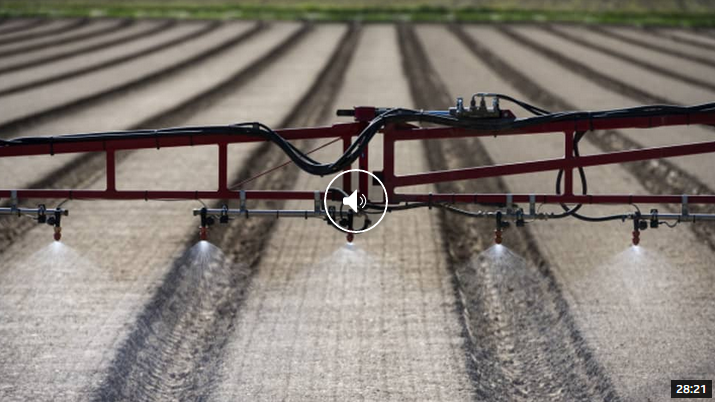 Eine Maschine besprüht Pestizide über ein Feld mit einem Sprühgerät.