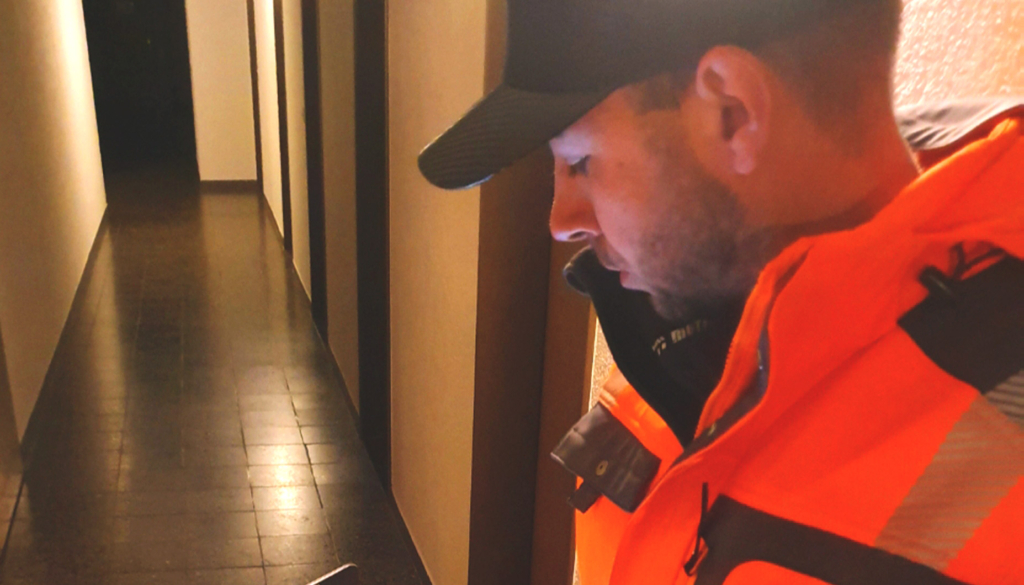 Ein Entwässerungstechnologe in einer orangefarbenen Jacke, der auf Notizen schaut.