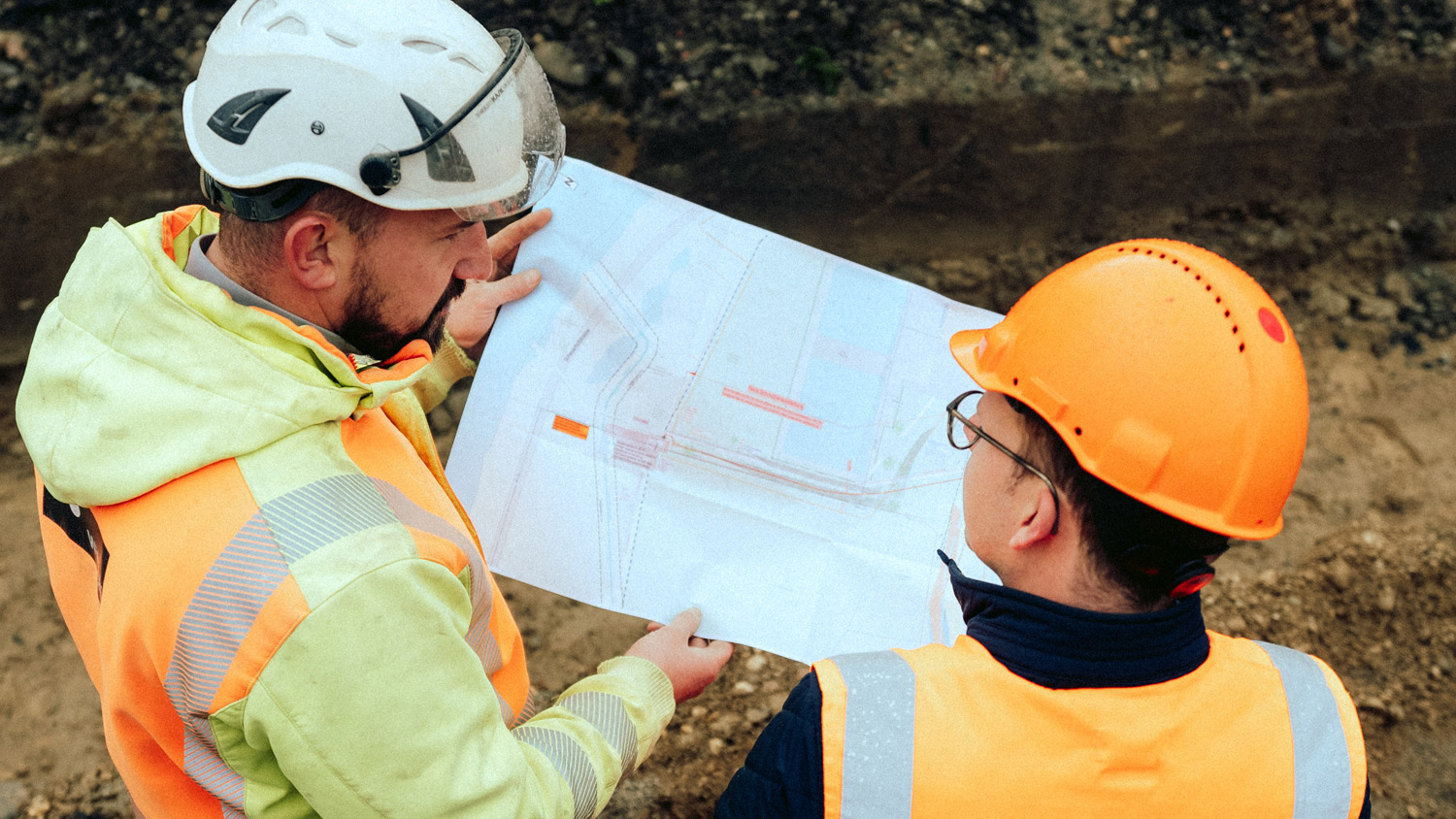 Zwei Bauleiter betrachten einen Plan.